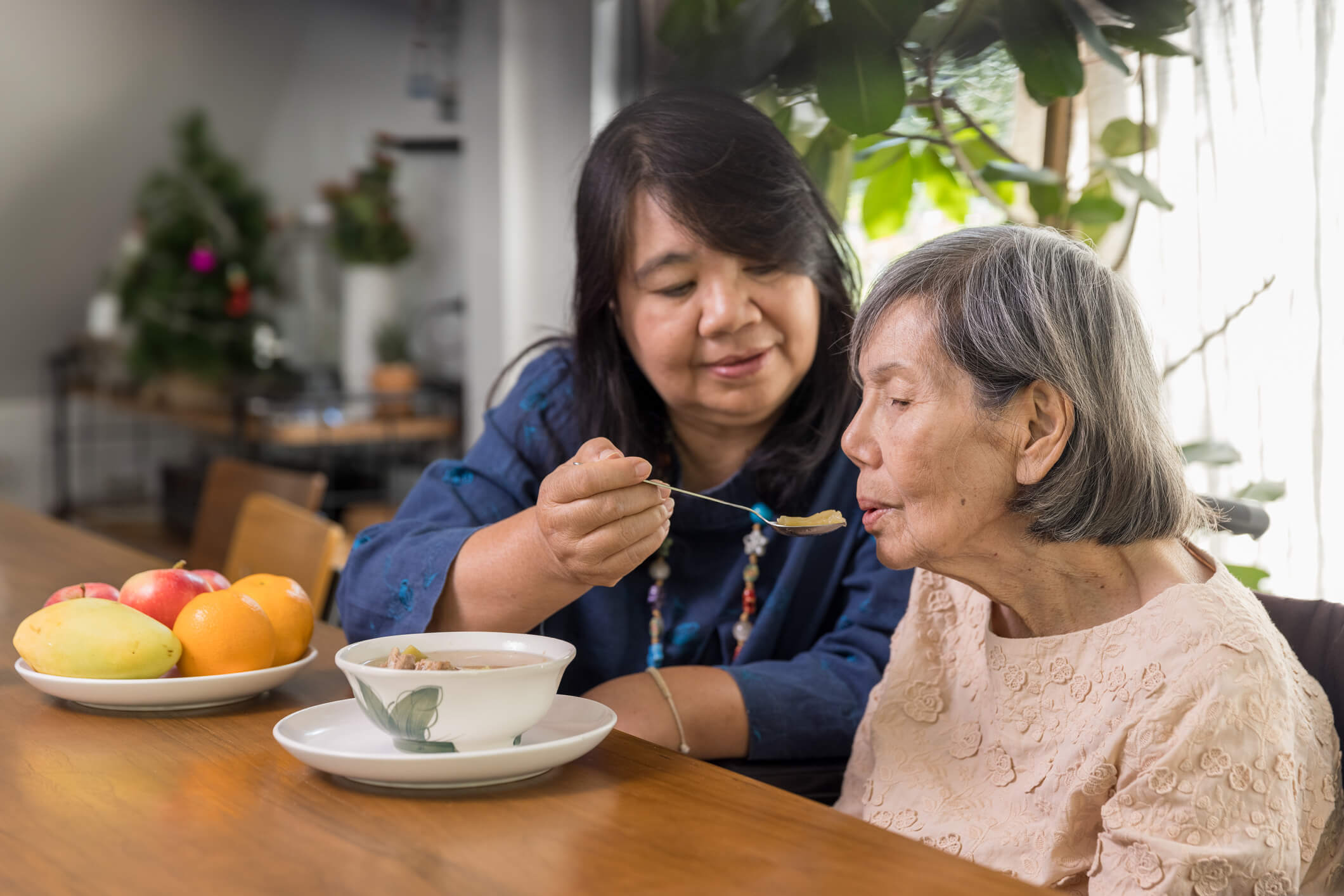 woman feeding dependent elderly mom