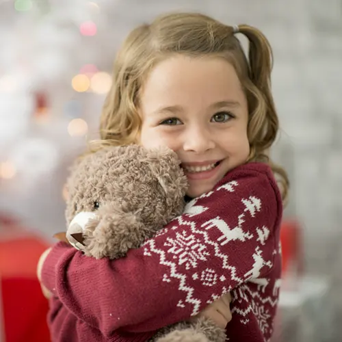 little girl hugging her teddy bear gift